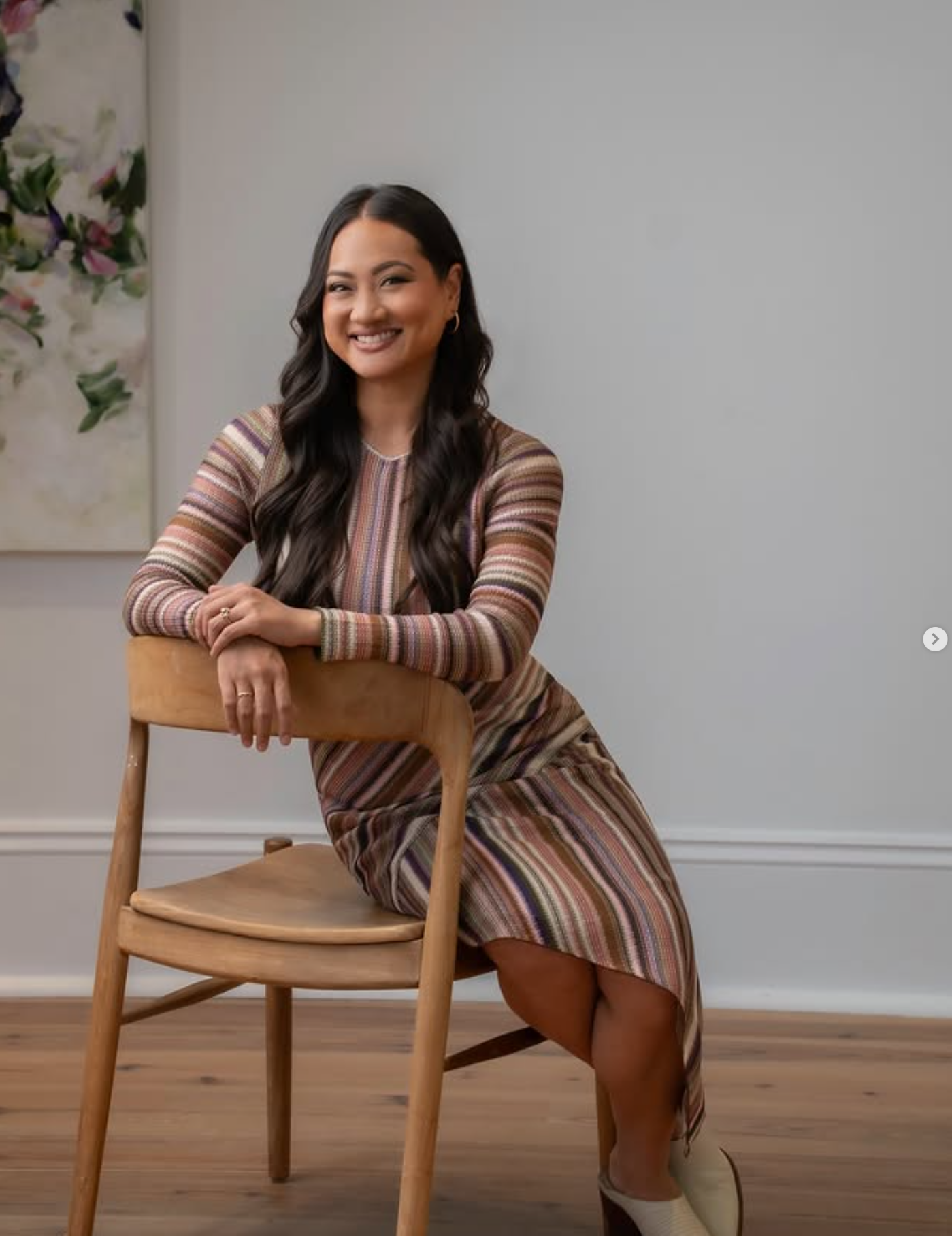 Professional portrait of a woman seated beside a chair